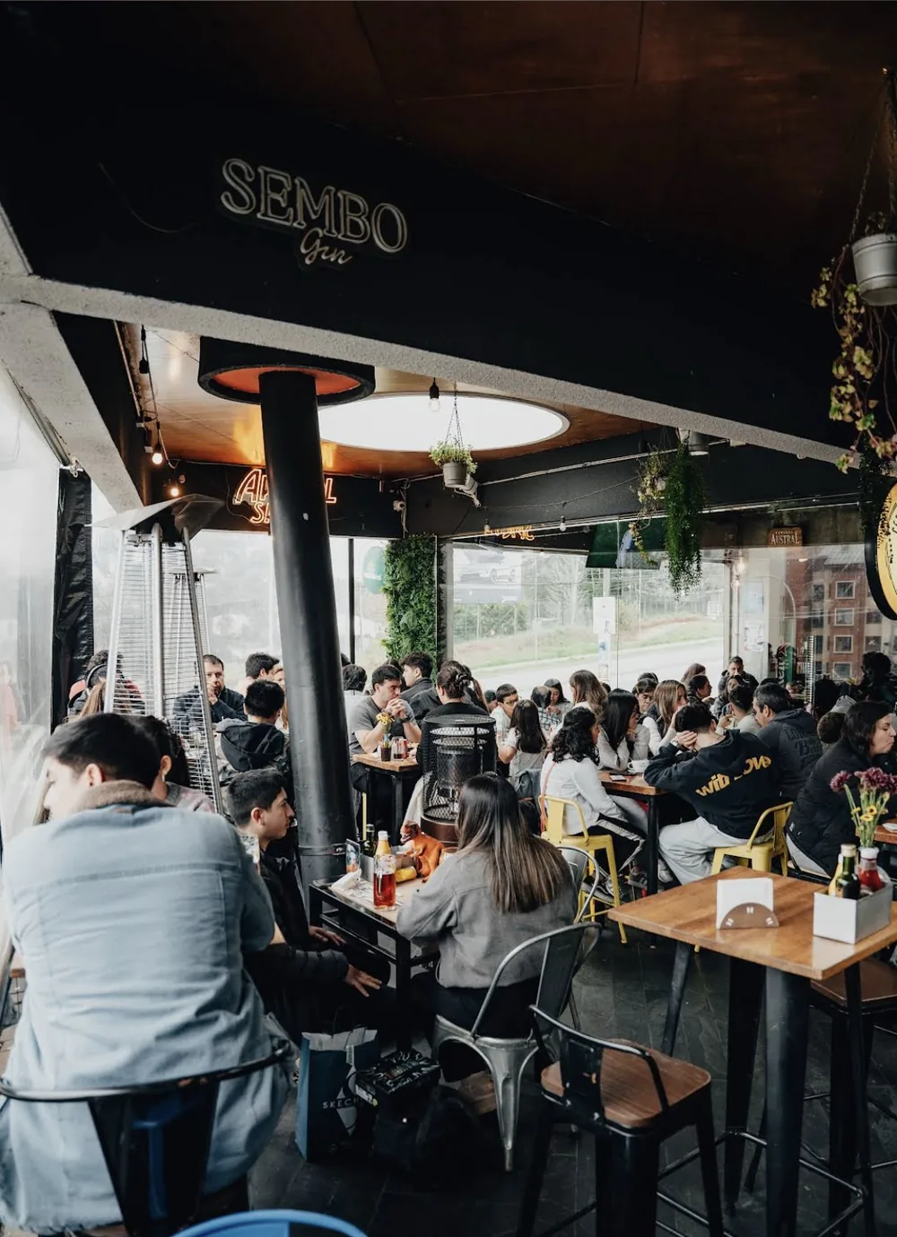 La terraza de Los Fundadores llena, con ventanales, mesas altas y el tragaluz redondo
