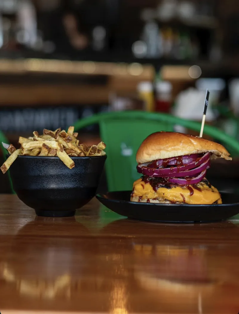 Juicy Lucy con cebolla morada y queso cheddar, junto a un bowl de papas fritas